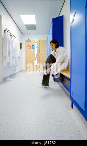 Une femme scientifique met sur les couvre-chaussures dans le vestiaire avant d'entrer dans un laboratoire stérile. Banque D'Images