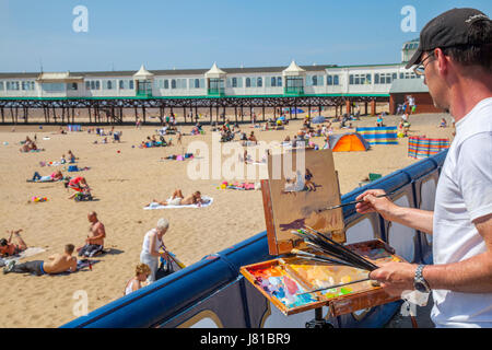 Lytham St Annes on Sea, Lancashire. Météo britannique. Paysagiste Norman Long 'peint la scène' sur la plage de Fylde comme foules affluent vers la jetée et resort zone front de mer pour profiter de l'ensoleillement d'été côtières près de Blackpool. Artiste de l'année en gagnant 2013 Norman a ouvert son premier one man show de Londres, la vie en ville, à Osborne Studio Gallery. Cette région rurale côtière Lancashire que gem est Lytham St Anne's Sandy Beach, qui abrite d'âne, une jetée victorienne et des aires de jeux pour enfants, à l'endroit idéal pour saisir l'essence de la station balnéaire. Banque D'Images