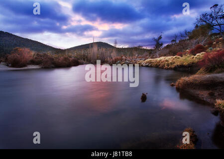 Coucher du soleil sombre dans la vallée de Thredbo sur Thredbo rivière dans les montagnes enneigées de l'Australie. Banque D'Images