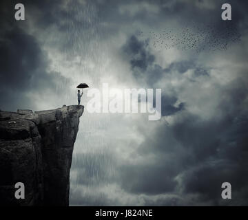 Homme avec un porte-parapluie sur le bord de la falaise, l'appel de la pluie. Lieu mystérieux au-dessus des nuages. Banque D'Images