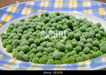 Petit pois Pois congelés sur une plaque blanche Banque D'Images