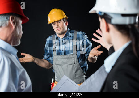 Deux architectes ingénieur en colère blâme dans hard hat sur noir Banque D'Images