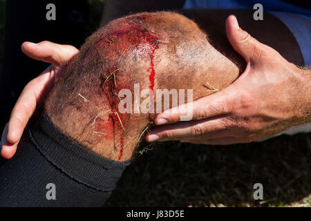 Close up of rugby player avec genou blessé assis sur terrain Banque D'Images