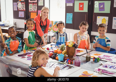 Portrait of smiling teacher et schoolkids en classe de dessin Banque D'Images