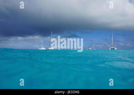 Seascape vu de surface de la mer, les voiliers et yachts ancrés dans la lagune et ciel nuageux, dans l'océan Pacifique, de l'atoll de Rangiroa, Tuamotu Banque D'Images