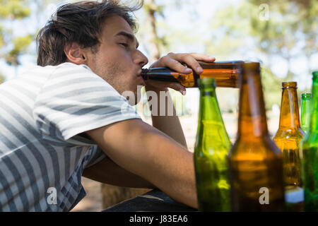 Homme inconscient de boire une bière en bouteille dans le parc Banque D'Images