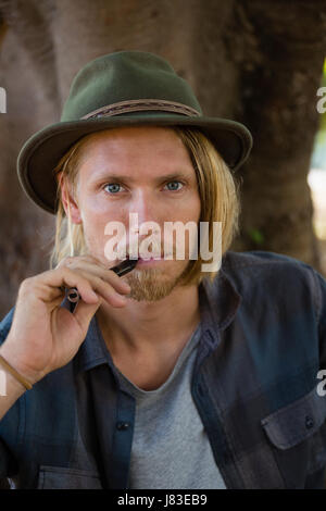 Portrait d'homme qui fume une cigarette électronique dans le parc Banque D'Images