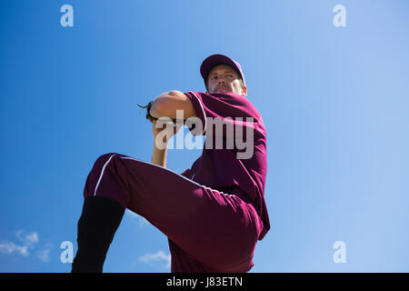 Low angle view of baseball pitcher throwing ball against blue sky sur sunny day Banque D'Images