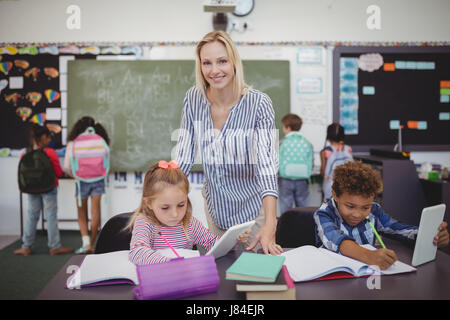 Aider les enseignants à faire leurs devoirs schoolkids en classe à l'école Banque D'Images