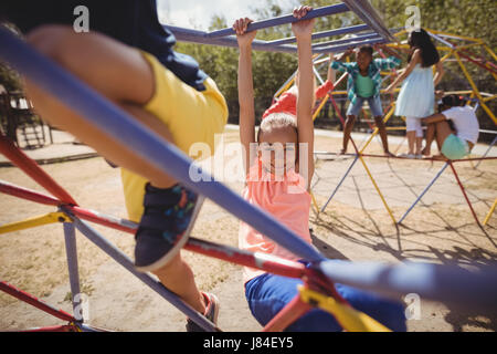 Portrait of happy girl playing on Monkey bar à l'école, aire de jeux Banque D'Images