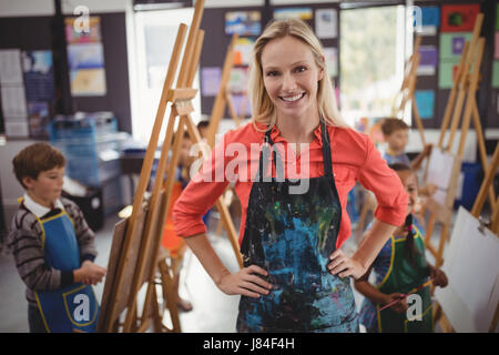 Portrait of smiling teacher standing hanche en classe de dessin Banque D'Images