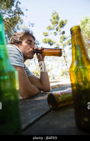 Homme inconscient de boire une bière en bouteille dans le parc Banque D'Images