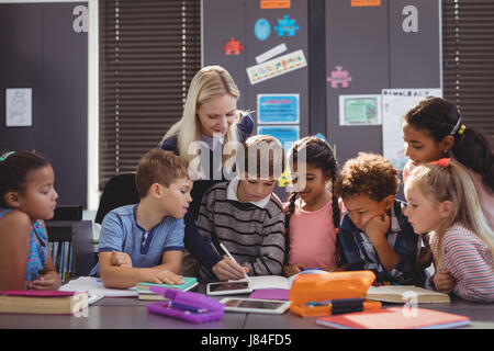 Aider les enseignants écolière avec ses devoirs en classe à l'école Banque D'Images