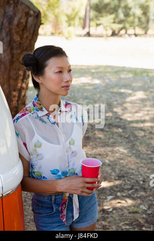 Young woman leaning on le camping-car dans le parc Banque D'Images