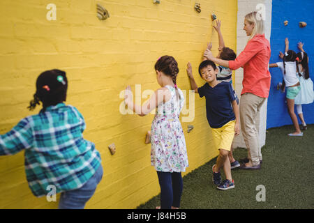 Aider les enfants en formateur mur d'escalade à l'école Banque D'Images