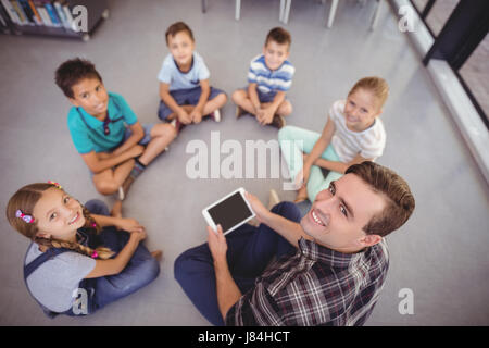 Vue de dessus de l'enseignant et schoolkids using digital tablet in library à l'école Banque D'Images