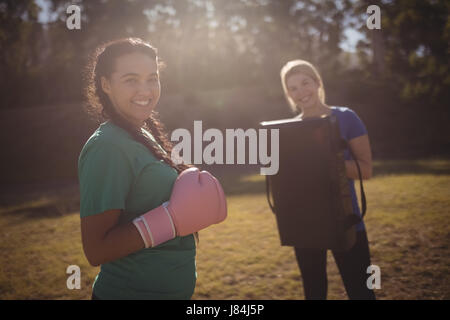 Portrait of happy woman wearing boxing gloves au cours de parcours dans boot camp Banque D'Images
