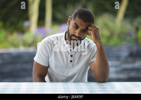 Contrarié man leaning on table au patio Banque D'Images