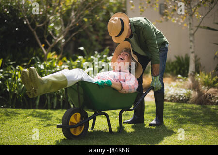 Senior man smiling woman in transport volant emprunter à yard Banque D'Images