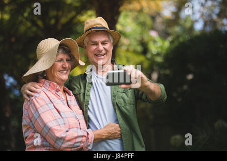 Happy senior couple prenant en selfies téléphone mobile en yard Banque D'Images