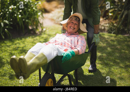 Mid section of man smiling senior femme en cour d'emprunter à roue Banque D'Images
