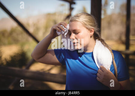 Fatigué woman wiping sweat après entraînement au cours de parcours dans boot camp Banque D'Images