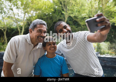 Happy family en tenant ensemble selfies at park Banque D'Images