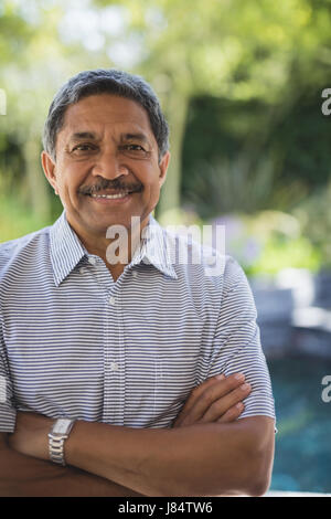 Portrait of smiling senior man with arms crossed standing à portique Banque D'Images