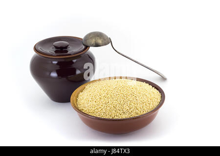 Still Life de mil en céréales, la pie-mère en céramique pot en céramique, vieille cuiller , isolé sur fond blanc Banque D'Images