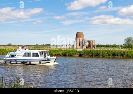 Un lancement sur la rivière Bure dans les Broads National Park passant St Benet's Abbey, Norfolk, Angleterre, Royaume-Uni. Banque D'Images