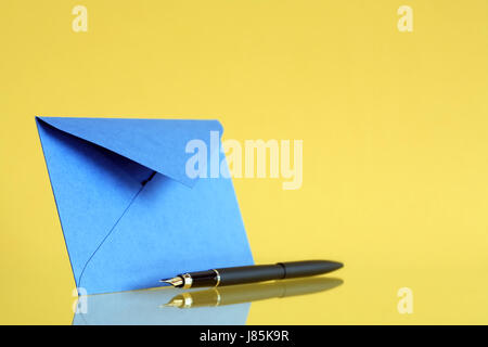 Enveloppe bleue près de stylo sur fond jaune Banque D'Images