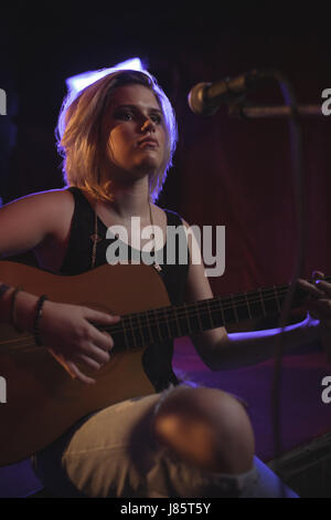 Chanteur pratiquant avec guitare en discothèque Banque D'Images