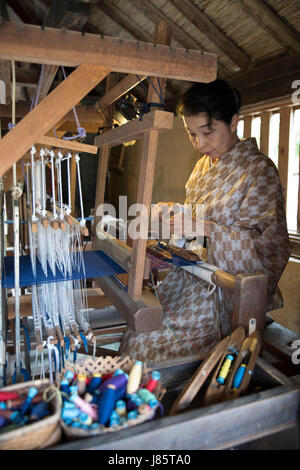La production à l'aide de chiffon femme Okinawa à tisser traditionnel. Ryukyu Mura, Village de Yomitan, Okinawa, Japon. Banque D'Images