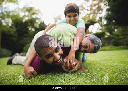Portrait of happy multi generation family playing rugby at park Banque D'Images