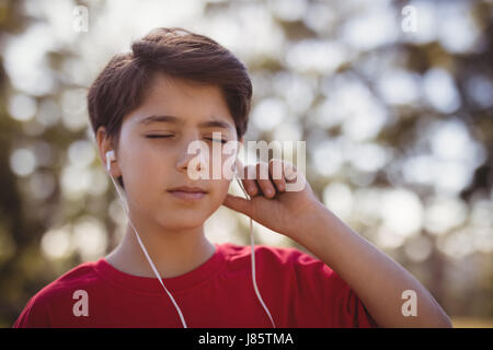 Close-up of boy listening music sur le casque au cours de parcours dans boot camp Banque D'Images