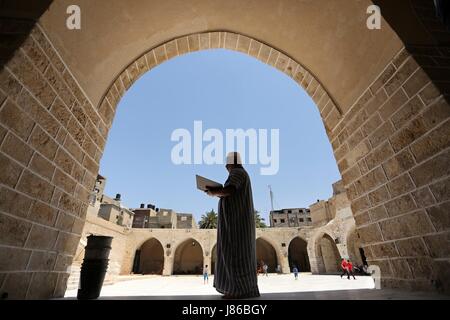 La ville de Gaza, bande de Gaza, territoire palestinien. 27 mai, 2017. Un Palestinien se lit un exemplaire du Coran, livre saint de l'Islam, le premier jour du jeûne dans le mois du Ramadan, à la mosquée al-Omari, dans la ville de Gaza, le 27 mai 2017. Le Ramadan est sacré pour les musulmans parce que c'est pendant ce mois que selon la tradition, le Coran a été révélé au prophète Mohammed. Le jeûne est l'une des cinq principales obligations religieuses sous l'Islam. Plus de 1. Banque D'Images