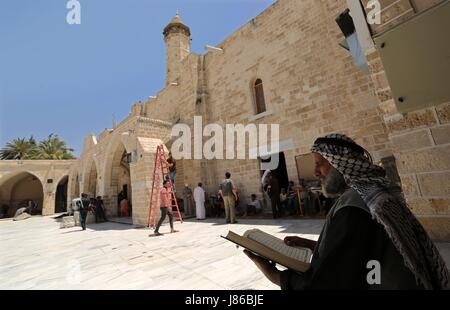 La ville de Gaza, bande de Gaza, territoire palestinien. 27 mai, 2017. Un Palestinien se lit un exemplaire du Coran, livre saint de l'Islam, le premier jour du jeûne dans le mois du Ramadan, à la mosquée al-Omari, dans la ville de Gaza, le 27 mai 2017. Le Ramadan est sacré pour les musulmans parce que c'est pendant ce mois que selon la tradition, le Coran a été révélé au prophète Mohammed. Le jeûne est l'une des cinq principales obligations religieuses sous l'Islam. Plus de 1. Banque D'Images