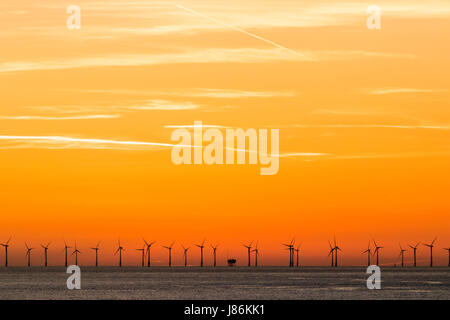 Aube du ciel orange sur le parc éolien offshore de Thanet avec rangée de turbines onon l'horizon. Éoliennes silhouetté contre le ciel orange vif. Banque D'Images