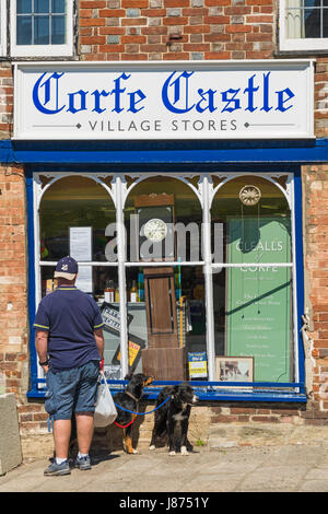 L'homme avec deux chiens à l'intérieur de château de Corfe Village Magasins à Corfe Castle, Dorset en mai Banque D'Images