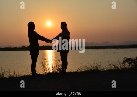 Des gens qui ont la main sur fond nature avec Sun, style silhouette Banque D'Images