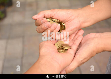 Pièce coulée palm main de femme dans la paume de mains d'hommes.Femmes pour les pièces de monnaie dans les mains d'une autre personne. Banque D'Images