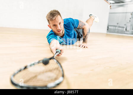 Formation de squash, football player avec racket se trouve sur le sol. Active sport d'entraînement. Jeu avec balle et raquette Banque D'Images