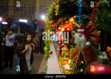 Santa Claus est perché sur l'arbre de Noël illuminé à Kakrail à Dhaka le Église la veille de Noël. Dhaka, Bangladesh Banque D'Images