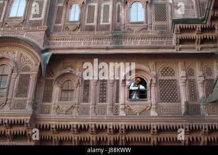 Un homme en tenue traditionnelle regarde par une fenêtre du palais à Jodhpur Fort, Rajasthan, Inde Banque D'Images