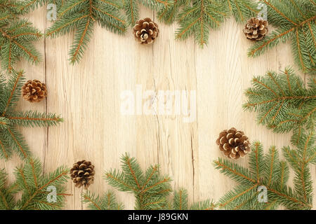 Cadre de Noël de sapin des brindilles et des pommes de pin sur fond en bois brun avec beaucoup d'espace de copie. Banque D'Images