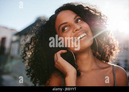 Portrait de jeune femme africaine avec des cheveux bouclés à la route. Les femmes afro-américaines à l'extérieur debout et souriant. Banque D'Images