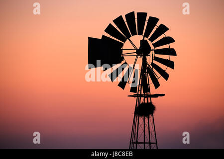 Un moulin à vent silhouetté contre un coucher de soleil rouge Banque D'Images