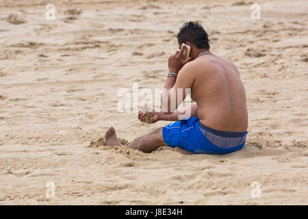 Bournemouth, Dorset, UK. 28 mai, 2017. UK : Météo des plages de Bournemouth à temps couvert, mais le soleil essaie de percer. Les visiteurs vers le bord de la tête pour tirer le meilleur de la Banque week-end de vacances. Young man sitting on beach en utilisant un téléphone mobile. Credit : Carolyn Jenkins/Alamy Live News Banque D'Images