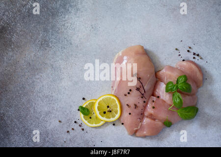 Matières premières fraîches filet de poulet avec le citron, les épices et le basilic sur la table de la cuisine. Arrière-plan de l'alimentation. Copier l'espace. Banque D'Images