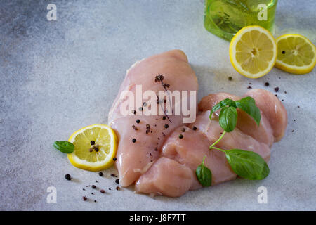 Matières premières fraîches filet de poulet avec le citron, les épices et le basilic sur la table de la cuisine. Arrière-plan de l'alimentation. Copier l'espace. Banque D'Images